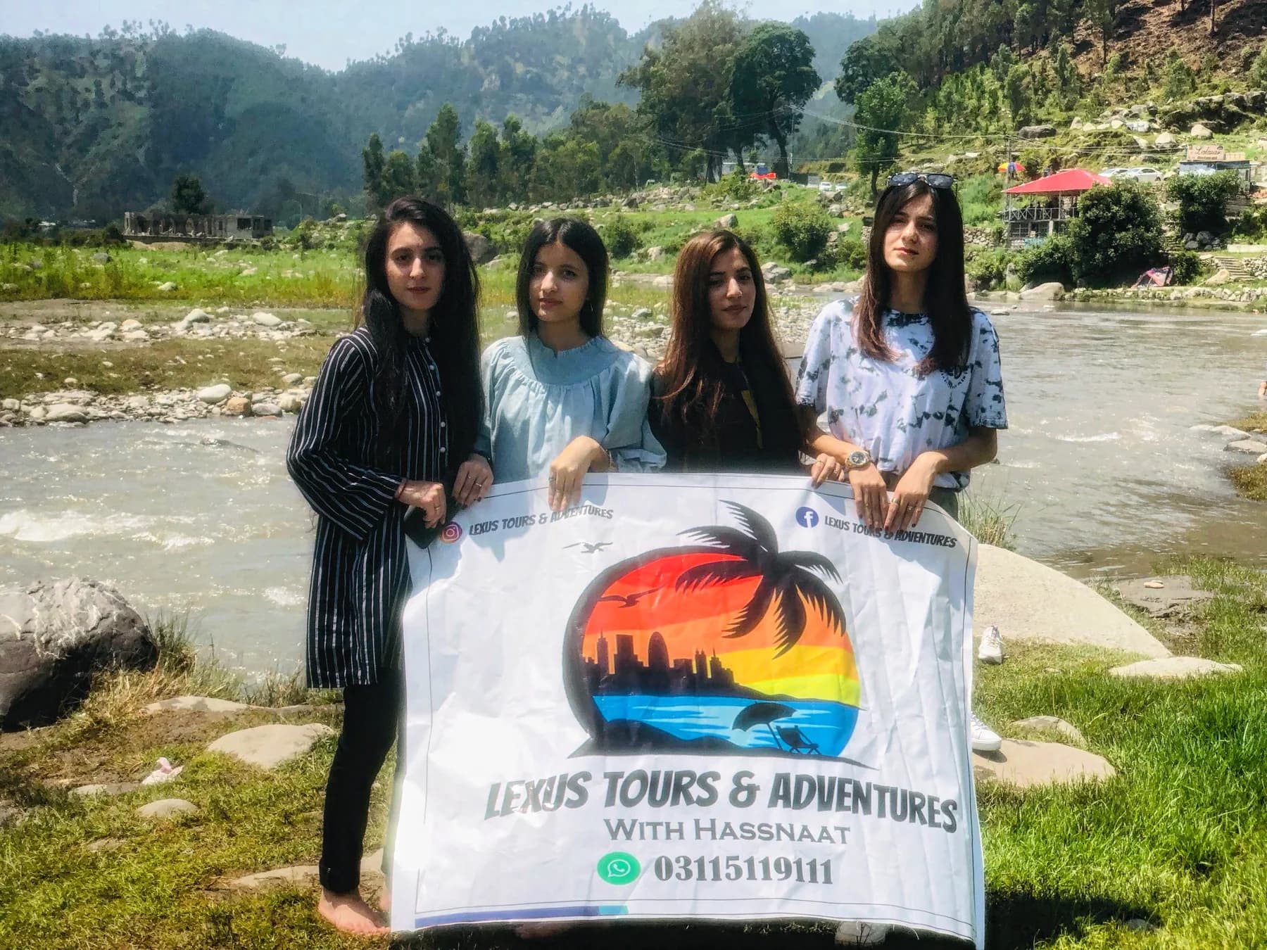 Travellers holding a Lexuz Tours banner beside a river